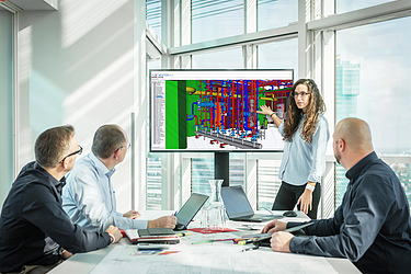 Person präsentiert einen farbigen 3D‑Gebäudetechnik‑Plan